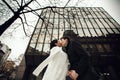 Newlyweds kiss under a huge glass building