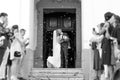 Newlyweds kissing while exiting the church after wedding ceremony, family and friends celebrating their love with the Royalty Free Stock Photo
