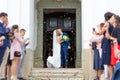 Newlyweds kissing while exiting the church after wedding ceremony, family and friends celebrating their love with the