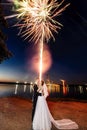 Newlyweds kissing near lake by night - fireworks