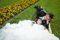 Newlyweds lying down on lawn with flowers Royalty Free Stock Photo