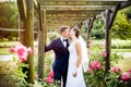Newlyweds in park rosarium next to beautiful pink roses