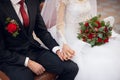 newlyweds sit on a chair with bouquet, hold each other's hands at the wedding ceremony Royalty Free Stock Photo