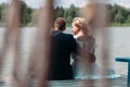 Newlyweds sitting back at lake on a wooden pier