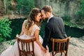 Newlyweds sitting at the edge of the canyon and couple looking each other with tenderness and love. Bride and groom