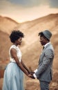 Newlyweds stand and hold hands in canyon against beautiful landscape.