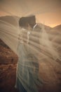 Newlyweds stand under bridal veil and embrace in canyon at sunset Royalty Free Stock Photo