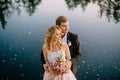 Newlyweds standing on the lake shore at sunset