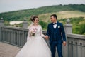 The newlyweds stroll along the parapet, laugh and discuss their wedding, holding hands.