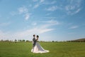 Newlyweds are walking along the green field of the golf club on a wedding day. The groom in a business suit is gray and Royalty Free Stock Photo