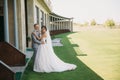 Newlyweds are walking along the green field of the golf club on a wedding day. The groom in a business suit is gray and Royalty Free Stock Photo