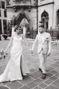 Newlyweds walking in the city centre in Europe. Beautiful wedding couple surrounded of old architecture. Black and white Royalty Free Stock Photo