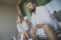 Newlyweds in white hotel gowns drink morning coffee on balcony