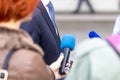 News conference, journalists with microphones interviewing politician or business person during media event