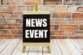 News Event text on the blackboard set on wooden floor and brick background Royalty Free Stock Photo