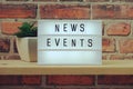 News Events word in light box on brick wall and wooden shelves background Royalty Free Stock Photo
