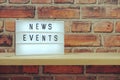 News Events word in light box on brick wall and wooden shelves background Royalty Free Stock Photo