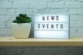 News Events word in light box on brick wall and wooden shelves background Royalty Free Stock Photo