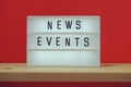 News Events word in light box on red and wooden shelves background