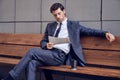 Daily news. Full length of a pleasant smiling businessman reading a newspaper with coffee while sitting on the bench Royalty Free Stock Photo