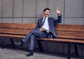 Daily news. Full length of a pleasant smiling businessman reading a newspaper with coffee while sitting on the bench