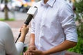 News journalist with microphone interviewing on street closeup Royalty Free Stock Photo