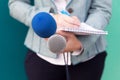 News reporter or TV journalist at press conference, holding microphone and writing notes Royalty Free Stock Photo