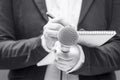 News reporter or TV journalist at press conference or media event, holding microphone and writing notes. Broadcast journalism. Royalty Free Stock Photo