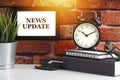 NEWS UPDATE text with alarm clock, books and vase on brick background Royalty Free Stock Photo