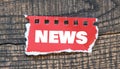 NEWS word written on a red iece of paper placed on a wooden table