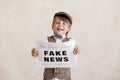 Newsboy shouting against grunge wall background. Boy selling fake news