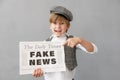 Newsboy shouting against grunge wall background. Boy selling fake news