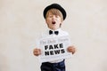 Newsboy shouting against grunge wall background. Boy selling fake news