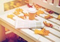 Newspaper and coffee cup on bench in autumn park Royalty Free Stock Photo