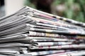 Newspapers folded and stacked on the table with gardenor green background. Closeup newspaper and selective focus image. Time to re