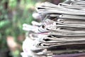Newspapers folded and stacked on the table with outdoor garden or green background. Closeup newspaper and selective focus image. T Royalty Free Stock Photo