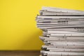 Newspapers folded and stacked on yellow background on the table