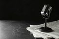 Newspapers and vintage microphone on dark stone table, space for text Royalty Free Stock Photo