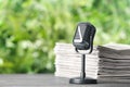 Newspapers and vintage microphone on grey table against blurred green background, space for text Royalty Free Stock Photo