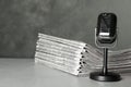 Newspapers and vintage microphone on light grey stone table. Journalist`s work Royalty Free Stock Photo
