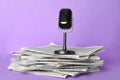 Newspapers and vintage microphone on light violet. Journalist`s work