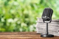 Newspapers and vintage microphone on table against blurred green background, space for text. Journalist`s work Royalty Free Stock Photo