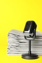 Newspapers and vintage microphone on yellow background Royalty Free Stock Photo