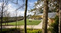 The Newt grounds framed by trees and Cyder bar / coffee shop - al fresco dining at The Newt, Somerset, UK