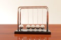 Newton`s cradle swinging on a wooden table with light background. Balance concept. Illustration 3d