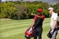 The next hole is that way. two men carrying their golf bags across a golf course and pointing at something. Royalty Free Stock Photo