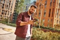 Next song. Cheerful young man with stubble in headphones listening to the music and holding mobile phone while standing Royalty Free Stock Photo