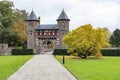 Next to this beautiful entrance gate of Kasteel De Haar there are trees in autumn colors in the grass