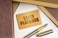 Next to the books lies a pen and a sign with the inscription - Sales playbook