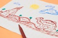 Next to the colored markers is a primitive children`s drawing with a felt-tip pen on a peach background. child development. Royalty Free Stock Photo